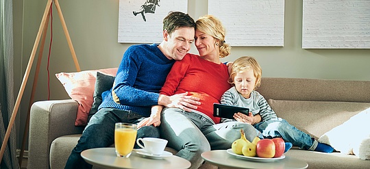 Glückliche Familie auf dem Sofa mit Handy
