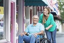 Mann im Rollstuhl mit pflegender Frau
