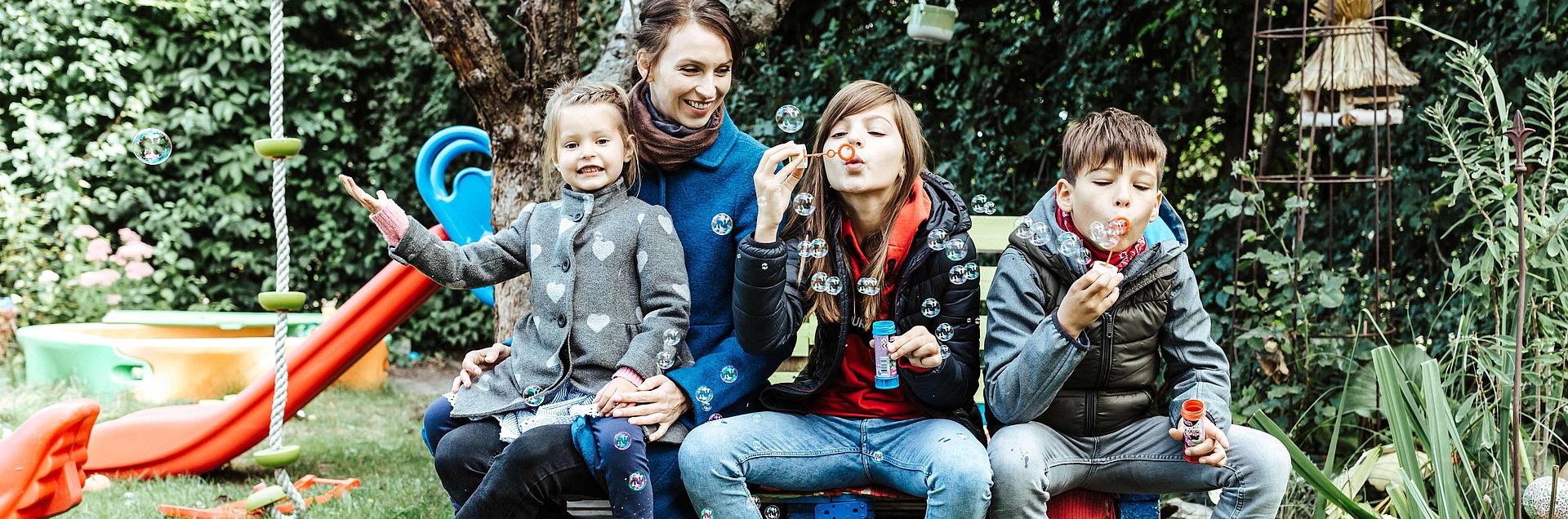 glückliche Familie im Garten macht Seifenblasen