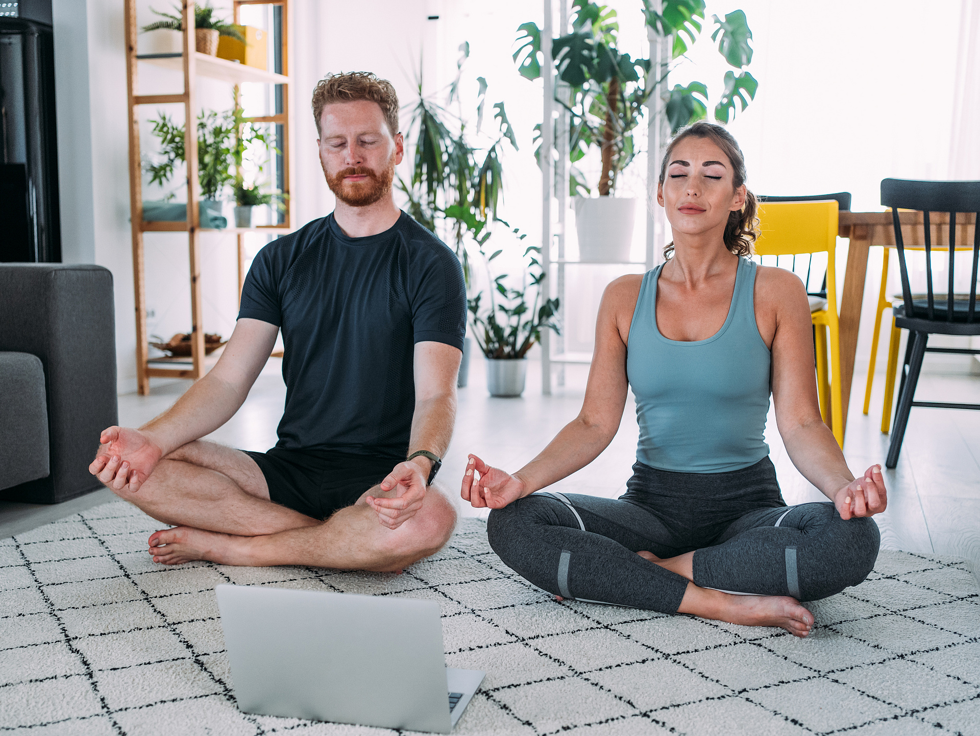Online Kurs - Stressbewältigung Mann und Frau im Schneidersitz machen Yoga im Wohnzimmer