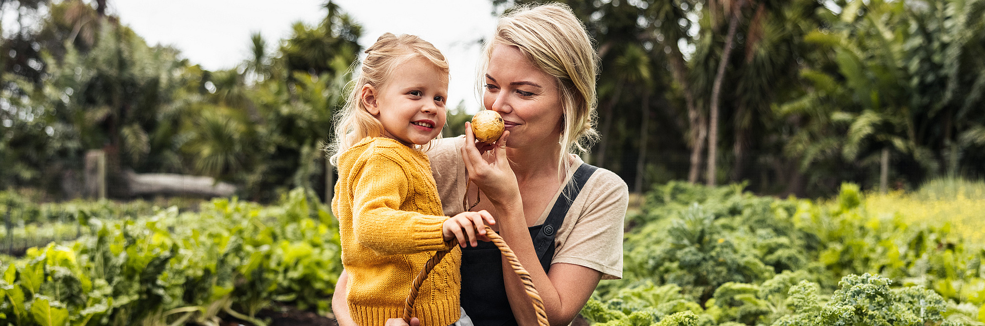 Frau mit Kind auf dem Arm in einem Gemüsefeld