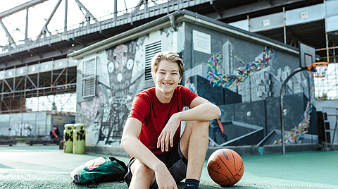 Junge sitzend mit Basketball