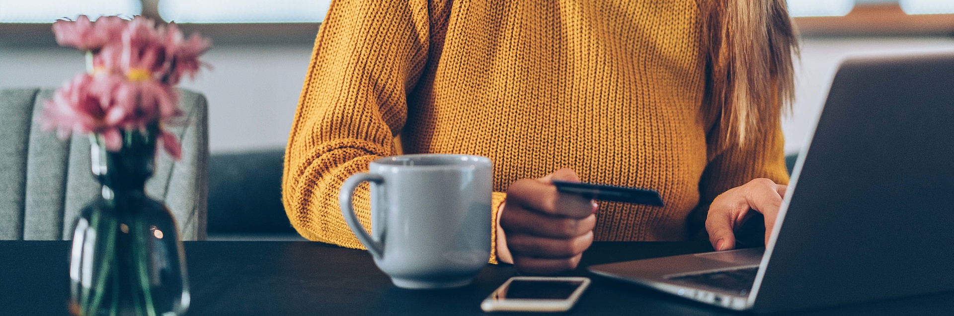 Frau am Laptop mit Gesundheitskarte in der Hand