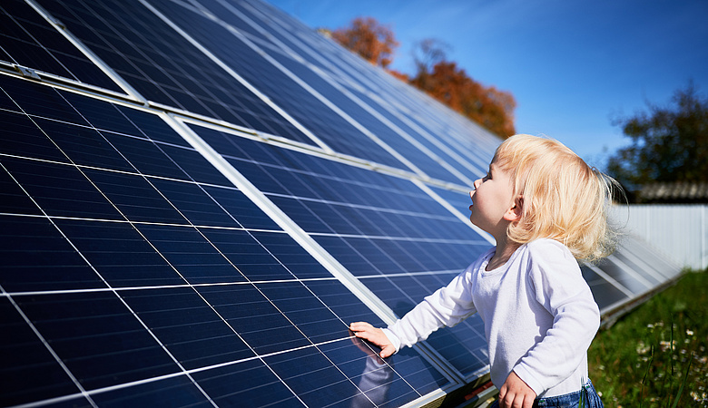 Kind steht vor einem Solardach, das bis auf den Boden reicht