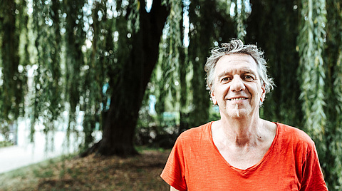 Älterer Mann der lächelt mit rotem Shirt