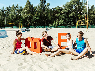 Jugendliche sitzen im Sand 