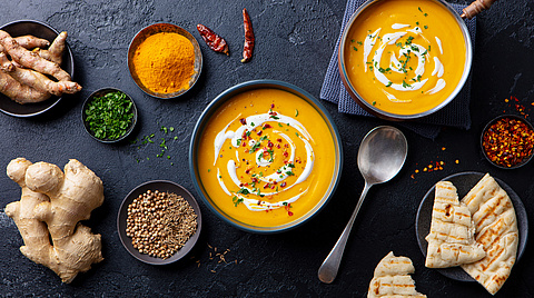 Tisch mit Kürbissuppe und Ingwer und verschiedenen Gewürzen