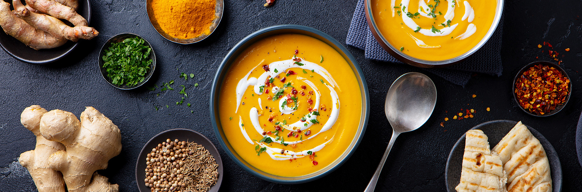 Tisch mit Kürbissuppe und Ingwer und verschiedenen Gewürzen 