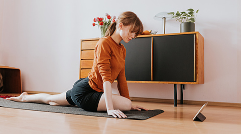 Frau sportliche Übung im Wohnzimmer vor Tablet