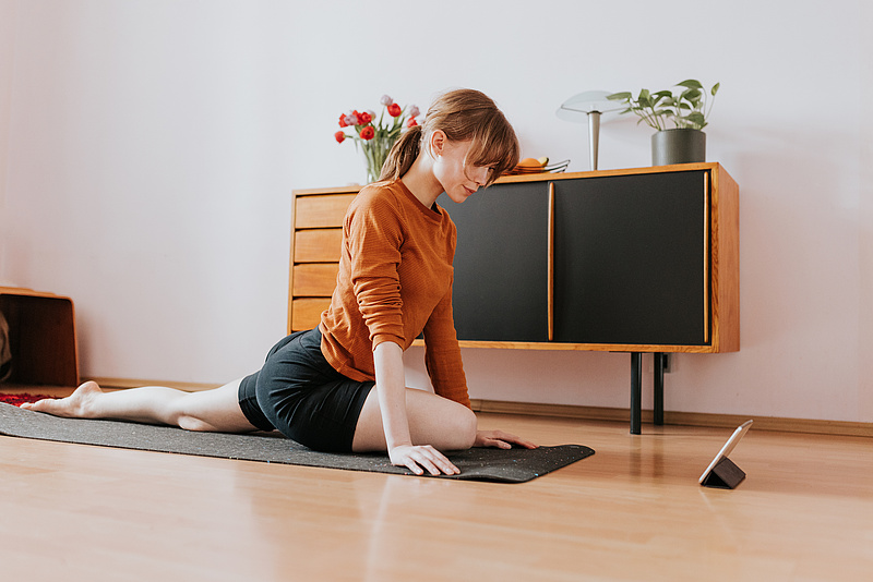 Frau sportliche Übung im Wohnzimmer vor Tablet