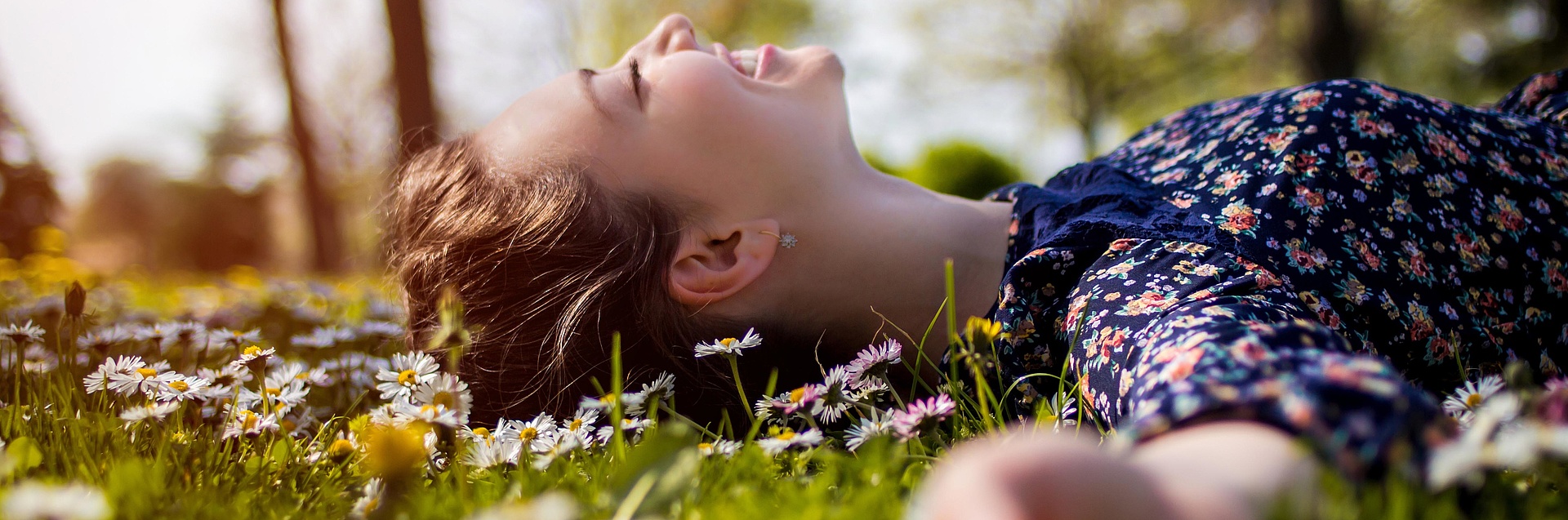 Frau liegt entspannt auf einer Blumenwiese